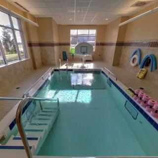 Indoor therapy pool with exercise equipment and bright natural lighting.