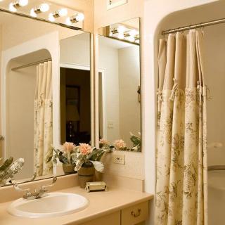 A well-lit bathroom with a sink, mirror, and floral shower curtain.
