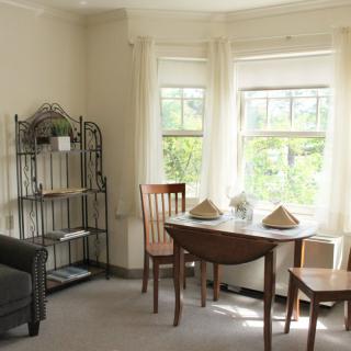 A cozy living room with a small dining table and chairs near a bright window.