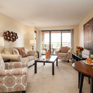 A cozy living room with comfortable seating, decorative accents, and a view of the balcony.