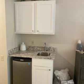 A compact kitchen area with a sink, countertop, cabinets, and a small refrigerator.