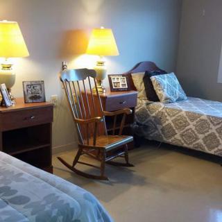 A cozy bedroom featuring twin beds, a rocking chair, and warmly lit lamps.