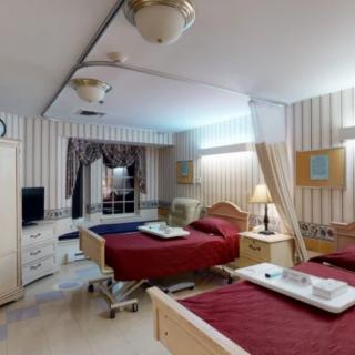 A hospital room with two beds and striped wallpaper.