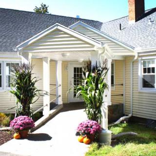 A residential house with a welcoming porch adorned with plants and flowers.