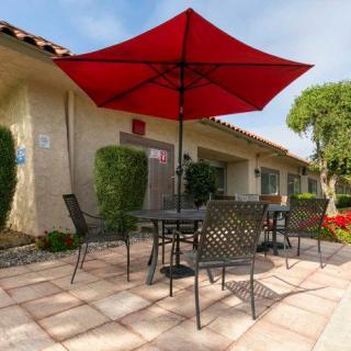 A sunny patio with a red umbrella and outdoor seating.
