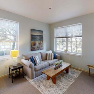 A cozy living room with a comfortable sofa, coffee table, and large windows.