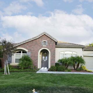 A single-story suburban house with a brick facade and a well-maintained lawn.