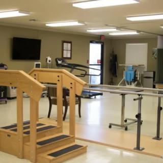 A physical therapy room equipped with parallel bars and a small staircase for rehabilitation exercises.