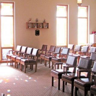 A serene chapel interior with rows of chairs and natural light streaming through tall windows.
