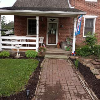 A charming brick house with a welcoming front porch and well-maintained landscaping.