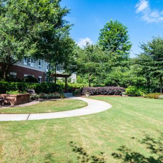 A scenic backyard garden featuring a lush lawn, curved pathway, and surrounding trees.