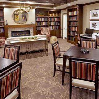Cozy library interior with bookshelves, a fireplace, and seating areas.
