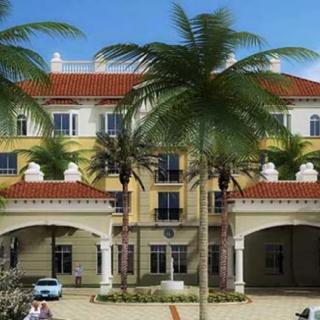 A Mediterranean-style residential building with palm trees in a sunny setting.