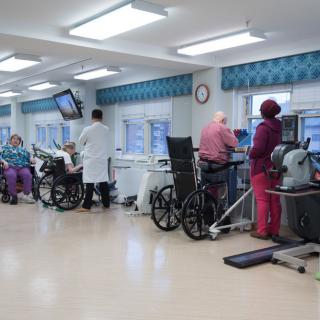 A rehabilitation center where patients are receiving physical therapy with the assistance of medical staff.