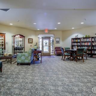 A cozy library interior with bookshelves, seating areas, and a carpeted floor.