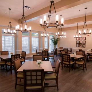 A cozy dining room with multiple tables, chairs, and elegant chandeliers.