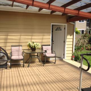 A cozy outdoor patio with seating and a small table, surrounded by a garden.