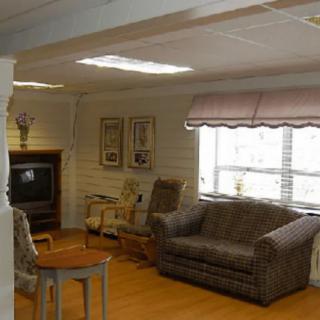 A cozy living room with a sofa, chairs, and a television near the window.