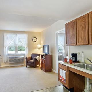 A cozy apartment living space featuring a kitchenette and a sitting area with natural light.