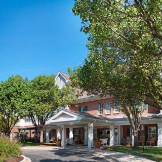 A view of a building entrance surrounded by trees and landscaping.