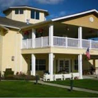 A two-story suburban house with a large porch and well-maintained lawn.