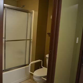 A bathroom with a shower and toilet featuring sliding glass doors.