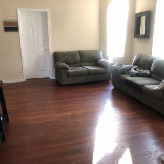 A cozy living room with two sofas and hardwood flooring, bathed in natural light.