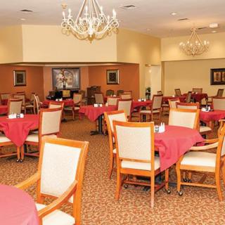 An elegant dining room with neatly arranged tables and chairs, decorated with chandeliers.
