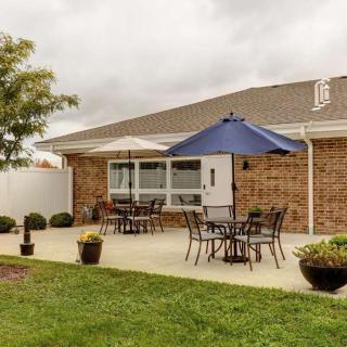 A peaceful backyard patio with tables, chairs, and a blue umbrella.