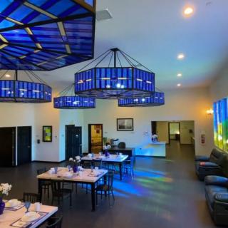A modern dining area with blue-lit chandeliers casting colorful reflections on the floor.