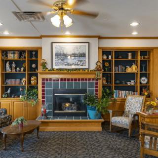 A cozy living room featuring a fireplace, surrounded by wooden bookshelves and comfortable seating.