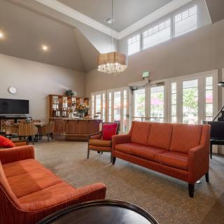 A cozy living room with orange sofas, a chandelier, and large windows.