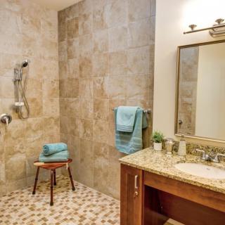A modern bathroom with a spacious walk-in shower and a granite vanity.