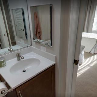 A modern bathroom with a sink and mirror adjacent to a bedroom.