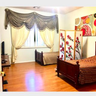 A cozy bedroom featuring a wooden floor, elegant curtains, and stylish decor.