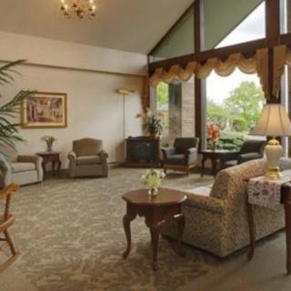 A cozy living room with traditional decor, featuring comfortable seating and large windows.