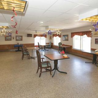 A spacious dining area with tables and chairs, adorned with ceiling decorations and well-lit by large windows.
