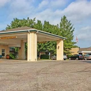 Entrance view of a hotel with a covered driveway and adjacent parking area.