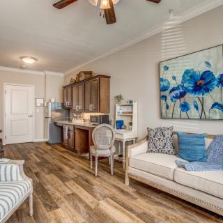 A cozy living area with a sofa, kitchenette, and vibrant artwork.