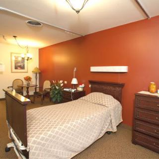 A cozy healthcare facility room with a hospital bed and warm decor.