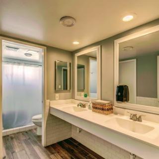 A sleek and modern bathroom featuring a dual vanity, large mirrors, and a shower enclosure.