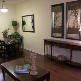 A cozy living room with elegant furniture and decorative artwork, featuring a dining table and mirrors on the walls.