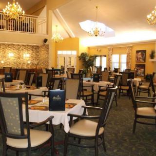 An elegant restaurant dining room with chandeliers and neatly arranged tables and chairs.