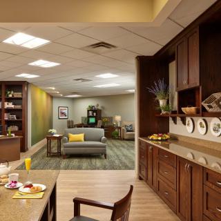 A cozy waiting room with a comfortable sofa, coffee table, and wooden cabinetry, featuring decorative plates and soft lighting.
