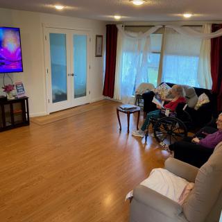 A group of people sitting on a sofa in a living room watching television.