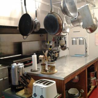 An industrial kitchen setup with hanging pots, a toaster, and a coffee maker on the countertop.