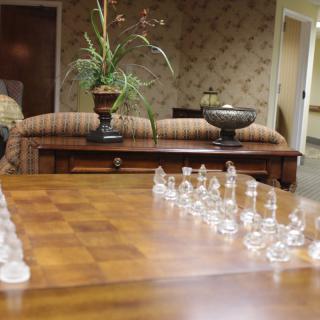 A lounge area featuring a wooden table with a glass chess set arranged for play.