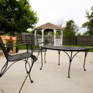 A backyard patio with metal furniture and a gazebo in the background.