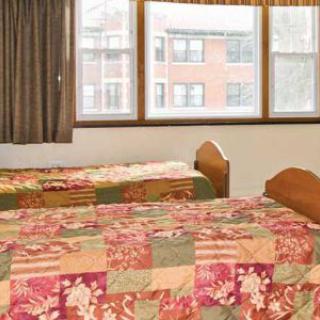 A bedroom with two twin beds, floral bedding, and a large window with curtains.