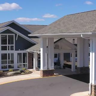 A modern residential building with a large driveway and prominent windows.